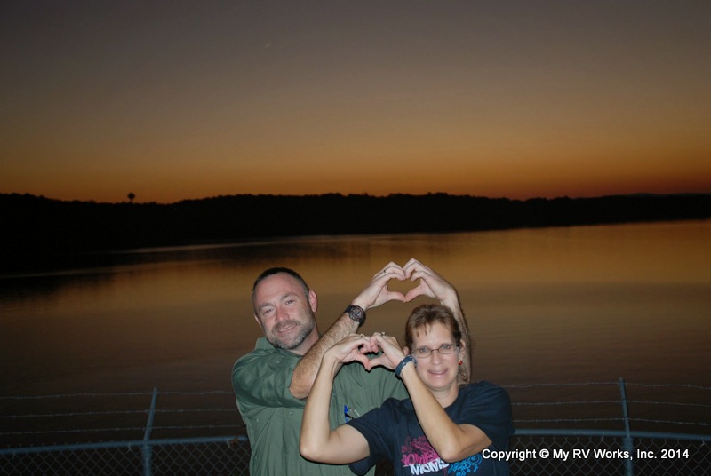 My RV Works Owners in front of a lake at night